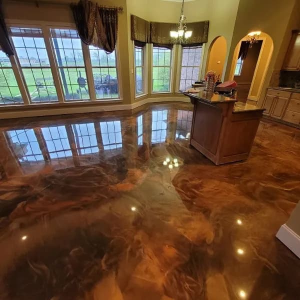 Glossy copper and brown marbled metallic floor reflecting tall windows and a chandelier beside a kitchen island.