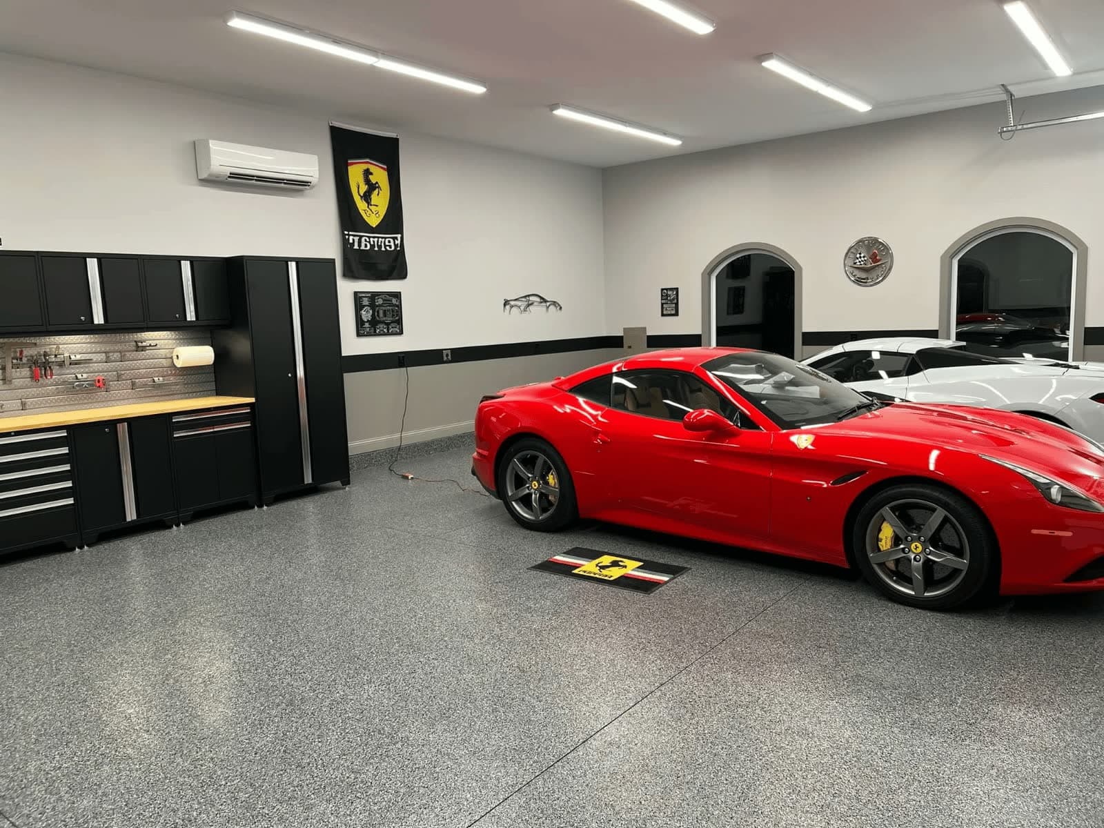 Grey and black flake epoxy garage floor in a home garage, with a red Ferrari and a white sports car parked over it.